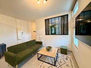 Le Jupiter, Centre ville, Parking Privé في بورجوا: غرفة معيشة مع أريكة خضراء وطاولة