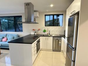 Albany Sunny Deck Retreat في أوكلاند: مطبخ بخزائن بيضاء وأريكة زرقاء