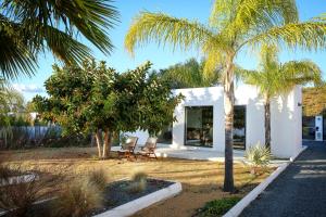 ein weißes Haus mit 2 Stühlen und Palmen in der Unterkunft Villa Guadiana Golf 1 in Ayamonte