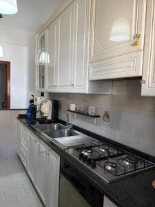 una cucina con mobili bianchi e un forno a piano cottura di Domus Poppea - a 5 minuti da Pompei e parcheggio gratuito a Torre Annunziata