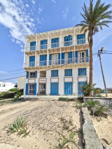 a white building with blue windows and a palm tree at Casa Albacora in Sal Rei