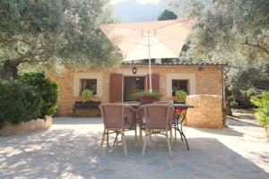 a table with chairs and an umbrella in front of a house at Casa Eva in Fornalutx