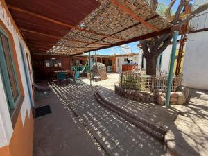 a patio with a wooden roof and a table and a tree at La Casa EcoExplor in San Pedro de Atacama