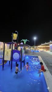 a group of children playing in a pool at night at شاليه جوري حتا-4-Chalet Jory Hatta in Būbādī