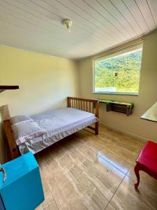 a bedroom with a bed and a window in it at Casa do Sol, Pássaros e Montanhas em Ubatuba Barra Seca in Ubatuba