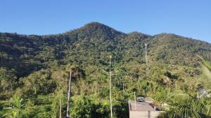 a mountain with trees on it with a house on it at Casa do Sol, Pássaros e Montanhas em Ubatuba Barra Seca in Ubatuba