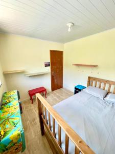 a bedroom with a bed and a red stool at Casa do Sol, Pássaros e Montanhas em Ubatuba Barra Seca in Ubatuba