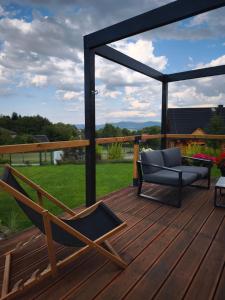 a wooden deck with a chair and a couch at Dom z widokiem na góry in Zawodzie