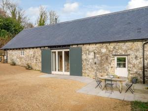 un cottage in pietra con tavolo e sedie di fronte di 2 Bed in Tisbury 78165 a Tisbury