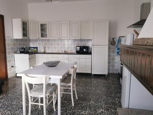 a kitchen with white cabinets and a table and chairs at Casa Bonaria in Terralba +15 photos