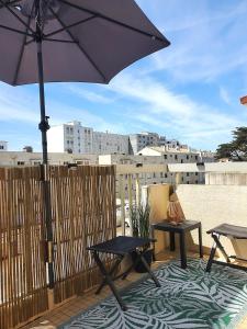 a patio with an umbrella and a table and chairs at Au Bord De L'eau, Proche plages in Saint-Jean-de-Monts