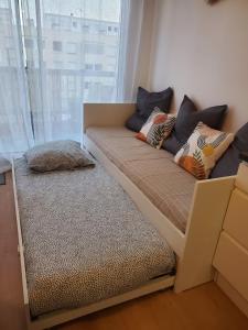 a bed with pillows on it in a room with a window at Au Bord De L'eau, Proche plages in Saint-Jean-de-Monts