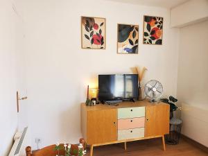 a living room with a tv on a wooden dresser at Au Bord De L'eau, Proche plages in Saint-Jean-de-Monts