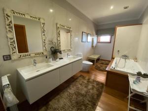 a bathroom with two sinks and a large mirror at Camélias Casa de Charme in Varziela +26 photos