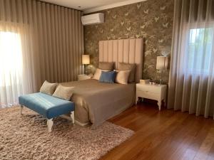 a bedroom with a large bed and a blue stool at Camélias Casa de Charme in Varziela