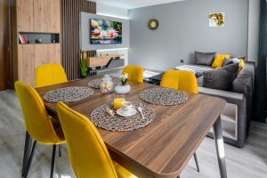 a dining room with a wooden table and yellow chairs at Cozy and Stylish Apartment 2 in Stara Zagora