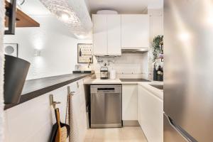 a kitchen with white cabinets and a stainless steel refrigerator at Manelinha Apartment - cozy apartment with pool and beach in Quarteira