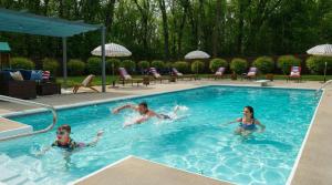 Pine & Paddle Getaway Game Room Hot Tub Pool في مسكيغون: 3 اطفال يسبحون في مسبح