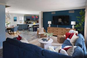 Pine & Paddle Getaway Game Room Hot Tub Pool في مسكيغون: غرفة معيشة مع أريكة زرقاء ومطبخ