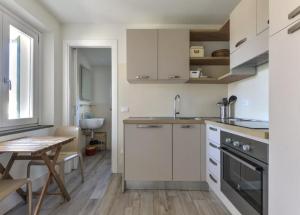 a kitchen with white cabinets and a table and a sink at Bilocale Pianosa - riservato e fresco a soli 10 m dal mare in Pomonte
