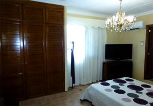 Un dormitorio con una cama, un televisor y una lámpara de araña. en Casa Villa Tenerife, en Las Galletas