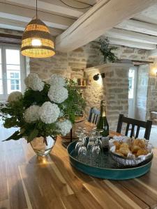 una mesa con un jarrón de flores y una botella de vino en Templar House With Pool Near Chablis, en Gigny