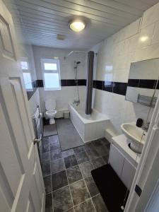 a bathroom with a tub and a toilet and a sink at Stunning 4 BedHouse Company Workers Welcome, Parking, Wifi, Netfix in Castleford