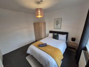 a bedroom with a bed with a yellow blanket on it at Stunning 4 BedHouse Company Workers Welcome, Parking, Wifi, Netfix in Castleford