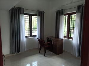 a desk with a chair in a room with windows at Liyano homestay in Palakkad