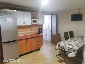 a kitchen with a counter and a table and a refrigerator at Casa Valea Cerbului Busteni in Buşteni