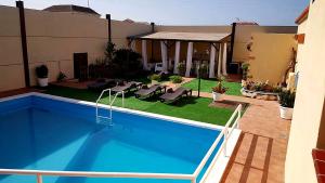 a house with a swimming pool with chairs and a patio at Casa Villa Tenerife in Las Galletas