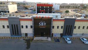 un gran edificio con un cartel en un estacionamiento en إس بي واي للشقق المخدومة - SBY Serviced Apartments, en Buraidah