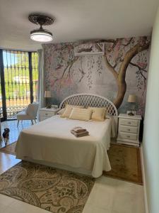 a bedroom with a bed and a tree mural at Bronlara in Alhaurín de la Torre