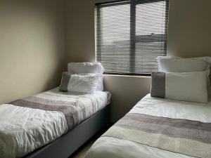 two beds sitting next to a window in a room at The Grey Ivory in Port Alfred