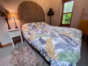 a bedroom with a bed with a bedspread with palm leaves at The Barn at Star Chamber Farm in Hebden Bridge