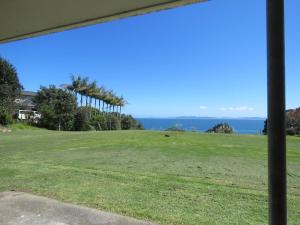 a view of a field with the ocean in the background at Coopers Haven- Beachfront House in Coopers Beach
