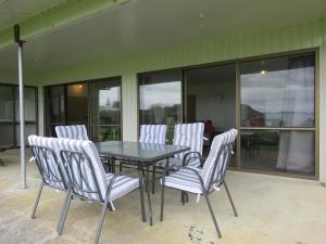 a black table and white chairs on a patio at Coopers Haven- Beachfront House in Coopers Beach