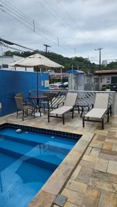 a patio with chairs and an umbrella next to a pool at Casa 23 em Condomínio à 700m da Praia dos Astúrias Guarujá - SP in Guarujá