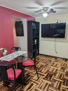 a dining room with a table and chairs and a tv at Apartamento Acogedor, tranquilo y privado in Lima