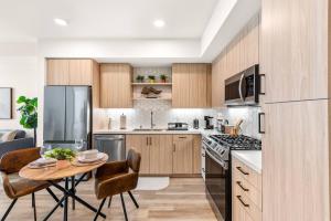 een keuken met houten kasten en een tafel met stoelen bij Fancy Irvine Apartment | Shopping + Dining in Paularino