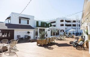 een houten terras met stoelen en tafels en een gebouw bij Fancy Irvine Apartment | Shopping + Dining in Paularino