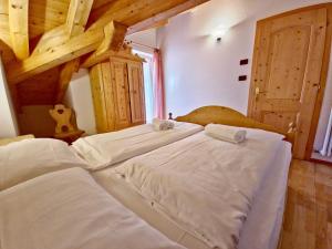 1 cama blanca grande en una habitación con techos de madera. en Villetta Clara by AMA Val di Fassa, en Vigo di Fassa