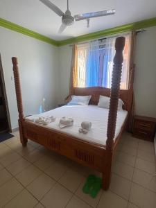 1 dormitorio con cama de madera y toallas en Jerres Inn, en Mtwapa