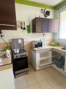 Una pequeña cocina con estufa y microondas. en Jerres Inn, en Mtwapa
