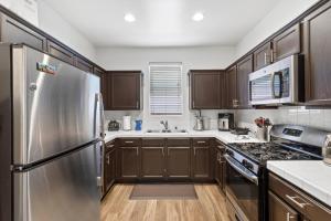 uma cozinha com armários de madeira e uma geladeira de aço inoxidável em Spacious Place 8 Mins To Disneyland *FREE Parking* em Tustin