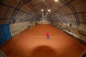 Tenis Pod Sosnami في Osieczów: شخص واقف على ملعب تنس