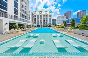 una piscina con sedie a sdraio e un edificio di Miami Skyline Residences by Untitled Stay a Miami