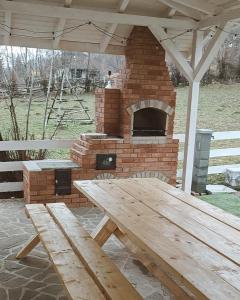 a picnic table in front of a brick oven at Cabana Gala Doftanei in Trăisteni
