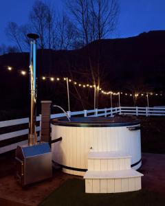 a hot tub with lights on a fence at night at Cabana Gala Doftanei in Trăisteni
