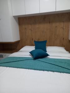a large bed with a blue pillow on it at SM apartman in Bijeljina